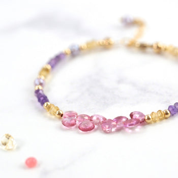 Handmade beaded bracelet with gold, purple, and pink beads.